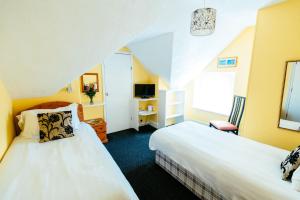 a hotel room with two beds and a tv at Surfside Stop in Newquay