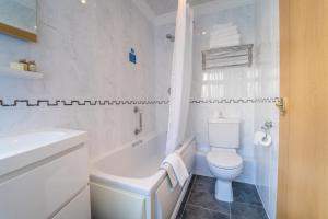 a white bathroom with a toilet and a tub and a sink at Atlantic Hotel in Tenby