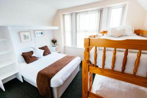 two bunk beds in a room with two windows at Surfside Stop in Newquay