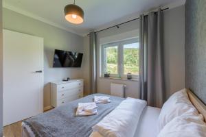 a bedroom with a bed with two towels on it at Apartament Tajemnica Izerska - 5D Apartamenty in Świeradów-Zdrój