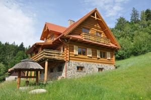 una casa de madera en una colina con césped en Dom Trzech Braci, en Lądek-Zdrój