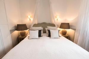 a bedroom with a white bed with two lamps at Le Pigeonnier in Saint-Tropez