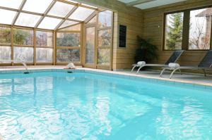 an indoor swimming pool with a conservatory with windows at Hôtel Restaurant La Tourmaline in Aime-La Plagne