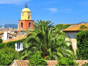 een klokkentoren bovenop een gebouw met een palmboom bij Le Pigeonnier in Saint-Tropez