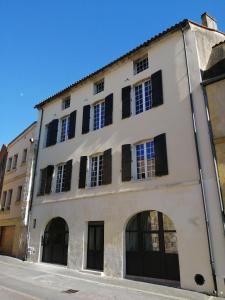 een wit gebouw met zwarte luiken bij Appartement de charme au coeur de Bergerac in Bergerac
