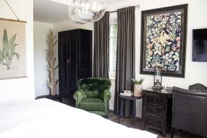 a bedroom with a bed and a green chair at Boutique Hotel Kauers in Verl