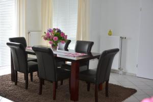una mesa de comedor con sillas negras y un jarrón de flores en Ferienwohnungen Steinhof-Littmann, en Kippenheim