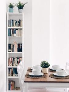 a dining room table with two chairs and a book shelf with books at Muy luminoso en San Mamés in Bilbao