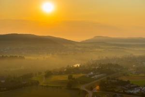 a misty sunrise with the sun rising over a city at Gasthof Hirschen in Gailingen