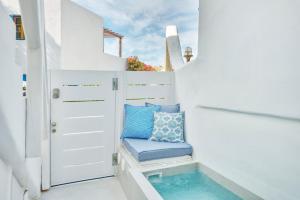 a small white room with a blue pillow on a stool at Mykonian Mews Luxury Suites in Psarou