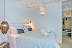 a bedroom with a white bed with white sheets and pillows at Mykonian Mews Luxury Suites in Psarou