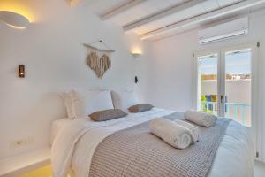 a white bedroom with a bed with towels on it at Mykonian Mews Luxury Suites in Psarou