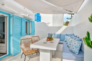a white and blue living room with a white table and chairs at Mykonian Mews Luxury Suites in Psarou