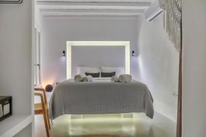 a white bedroom with a bed with two towels on it at Mykonian Mews Luxury Suites in Psarou