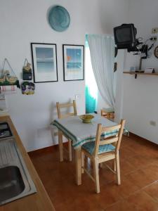 cocina con mesa y sillas y TV en Casa La Fornace, en La Maddalena