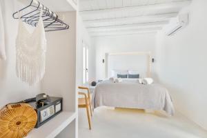 a white bedroom with a bed and a table at Mykonian Mews Luxury Suites in Psarou
