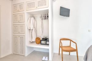 a room with a closet with a chair and a tv at Mykonian Mews Luxury Suites in Psarou