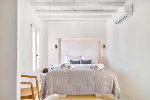 a white bedroom with a bed with two towels on it at Mykonian Mews Luxury Suites in Psarou