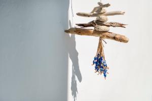 a cross hanging on a wall with rocks and beads at Mykonian Mews Luxury Suites in Psarou