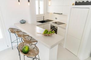 a white kitchen with a bowl of fruit on a counter at Mykonian Mews Luxury Suites in Psarou