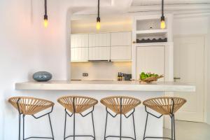 a kitchen with a counter and four stools at Mykonian Mews Luxury Suites in Psarou