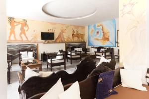 a living room with chairs and paintings on the walls at Gardenia Hotel in Perissa