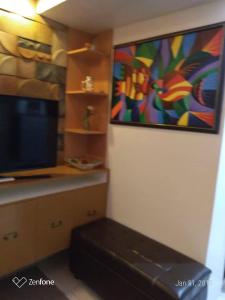 a living room with a television and a painting on the wall at HappyNest 1857 @ Cityland Tagaytay in Tagaytay