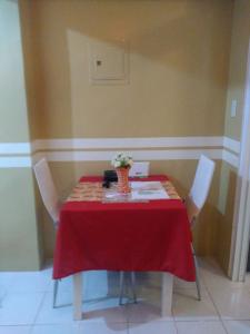 a red table with chairs and a vase of flowers on it at HappyNest 1857 @ Cityland Tagaytay in Tagaytay