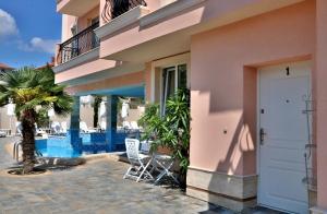 a building with chairs and a palm tree next to a pool at Sirena Palace Family Hotel in Obzor