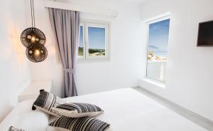 a white room with windows and a bed with pillows at Arkasa Palace in Arkasa