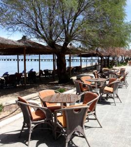 una fila de mesas y sillas junto al agua en Noni Rooms en Agia Triada