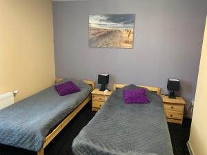 two beds in a room with purple pillows at Portoss in Ventspils