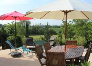 a patio with a table and chairs with umbrellas at La Villanelle maison d'hôtes in Pelousey