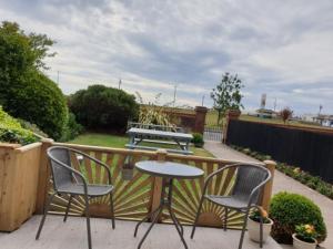 un patio con 2 sillas y una mesa en el balcón en Sefton Lodge SEAFRONT ,PANORAMIC SEA VIEW ENSUITE BALCONY ROOMS AVAILABLE, GUEST GARDEN, en Paignton