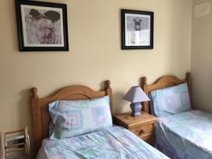 een slaapkamer met 2 bedden en een tafel met een lamp bij Cliff Cottages in Liscannor