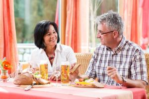 un hombre y una mujer sentados en una mesa comiendo comida en Café-Pension Kristall, en Harbach