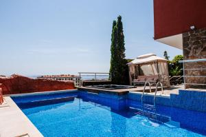 a blue swimming pool with a gazebo next to the ocean at Red Iguana Hotel in Sveti Vlas