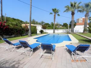 un grupo de sillas y una piscina con palmeras en VILLA EN LES ROTES/LAS ROTAS, PISCINA, en Denia