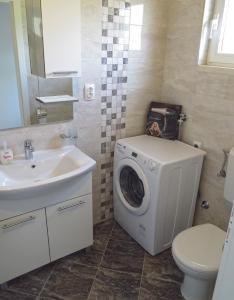 a bathroom with a washing machine next to a sink at Jakopovic Apartments in Rogoznica