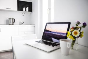 a laptop computer sitting on a table with a vase of flowers at SurfersResidence Apartments in Tarifa