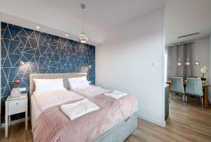 グダニスクにあるLive & Travel Apartments Number 1のベッドルーム1室(ブルーアクセントの壁の大型ベッド1台付)