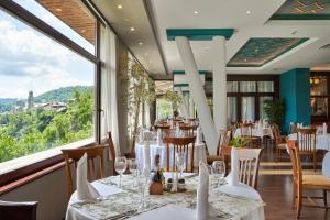 a restaurant with tables and chairs and a large window at Yantra Grand Hotel in Veliko Tŭrnovo