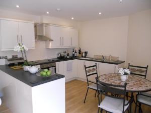 a kitchen with white cabinets and a table and chairs at The Auction House in Ryde