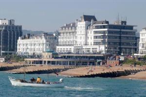 a boat in the water near a beach with buildings at Cavendish Hotel in Eastbourne
