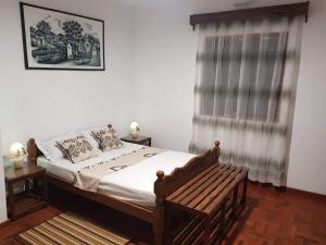 1 dormitorio con cama, ventana y banco en Chambre d'hôtes Valiha en Ivato