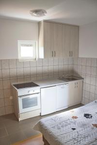 La cuisine est équipée de placards blancs, d'un évier et d'une cuisinière. dans l'établissement Apartment ANGELINA, à Trebinje