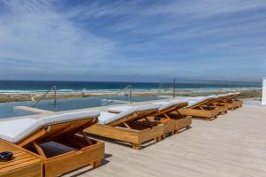 a row of deckchairs with the ocean in the background at Zahara Beach & Spa by QHotels - Adults Recommended in Zahara de los Atunes