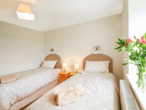 a bedroom with two beds and a vase of flowers at Coed Bolyn Lodge in Llanddeiniolen