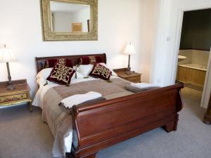 a bedroom with a bed with pillows and a mirror at Old Barns - Pentre Berw in Llangristiolus