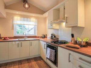 a kitchen with white cabinets and a stove top oven at Little Bakehouse in Criccieth